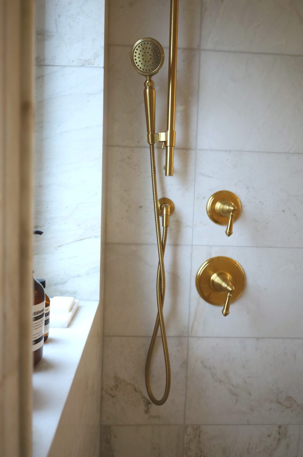 Brass shower fixtures against marble tile — Midtown Toronto interior design by Erica Yolevski Design Studio